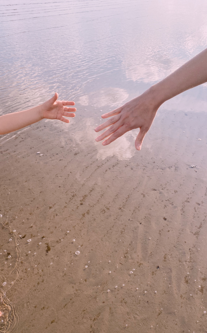 Woman’s hand reaching out to a child’s hand